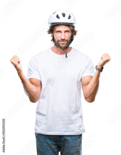 Handsome hispanic cyclist man wearing safety helmet over isolated background celebrating surprised and amazed for success with arms raised and open eyes. Winner concept.