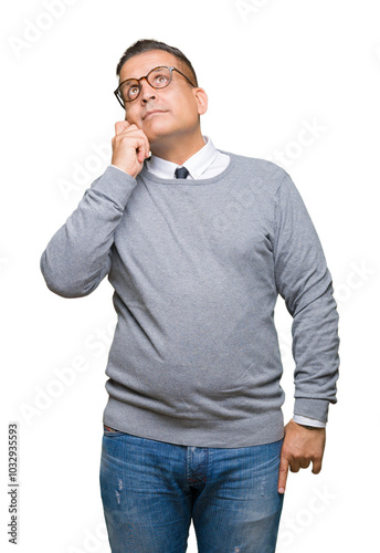 Middle age bussines arab man wearing glasses over isolated background with hand on chin thinking about question, pensive expression. Smiling with thoughtful face. Doubt concept.