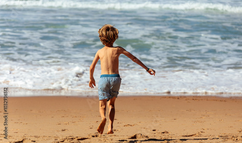 Fototapeta Naklejka Na Ścianę i Meble -  Small Blond Boy Running Towards the Sea in Portugal