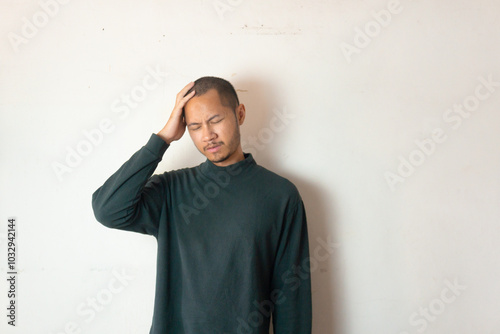 Young men wearing green sweater having headache on isolated white background photo