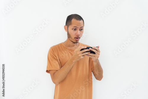 Young men wearing orange shirt is happy playing game using phone on isolated white background photo