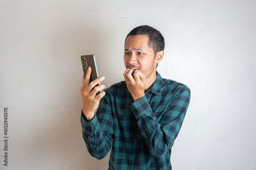 Young men wearing green flannel is scared with phone on isolated white background Young men wearing green flannel is scared with phone on isolated white background
