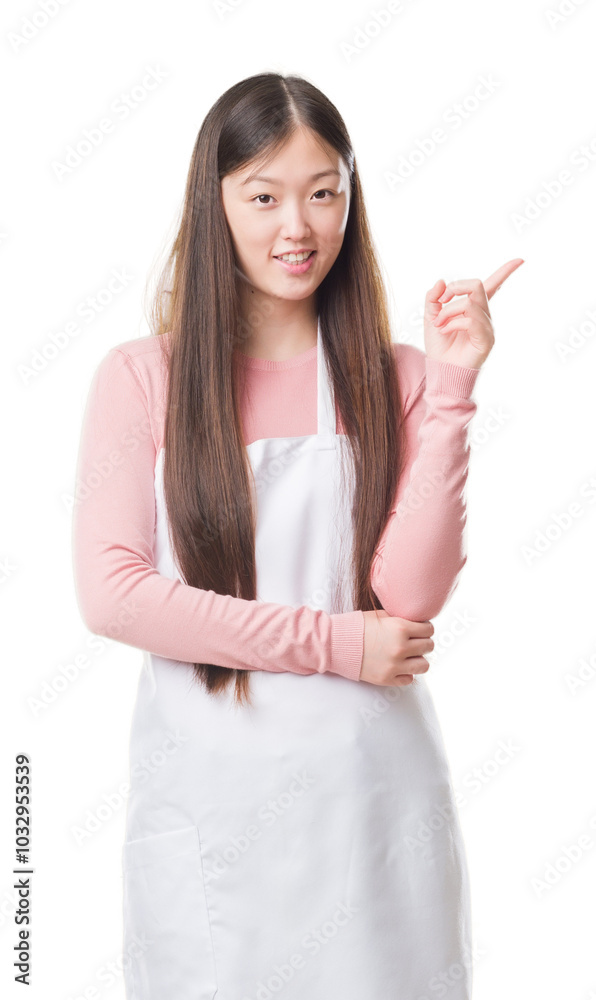 Young Chinese shop owner woman over isolated background wearing white apron very happy pointing with hand and finger to the side Young Chinese shop owner woman over isolated background wearing white apron very happy pointing with hand and finger to the side