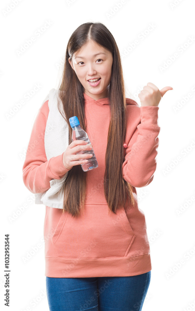 Young Chinese woman over isolated background wearing sport sweathshirt pointing and showing with thumb up to the side with happy face smiling Young Chinese woman over isolated background wearing sport sweathshirt pointing and showing with thumb up to the side with happy face smiling