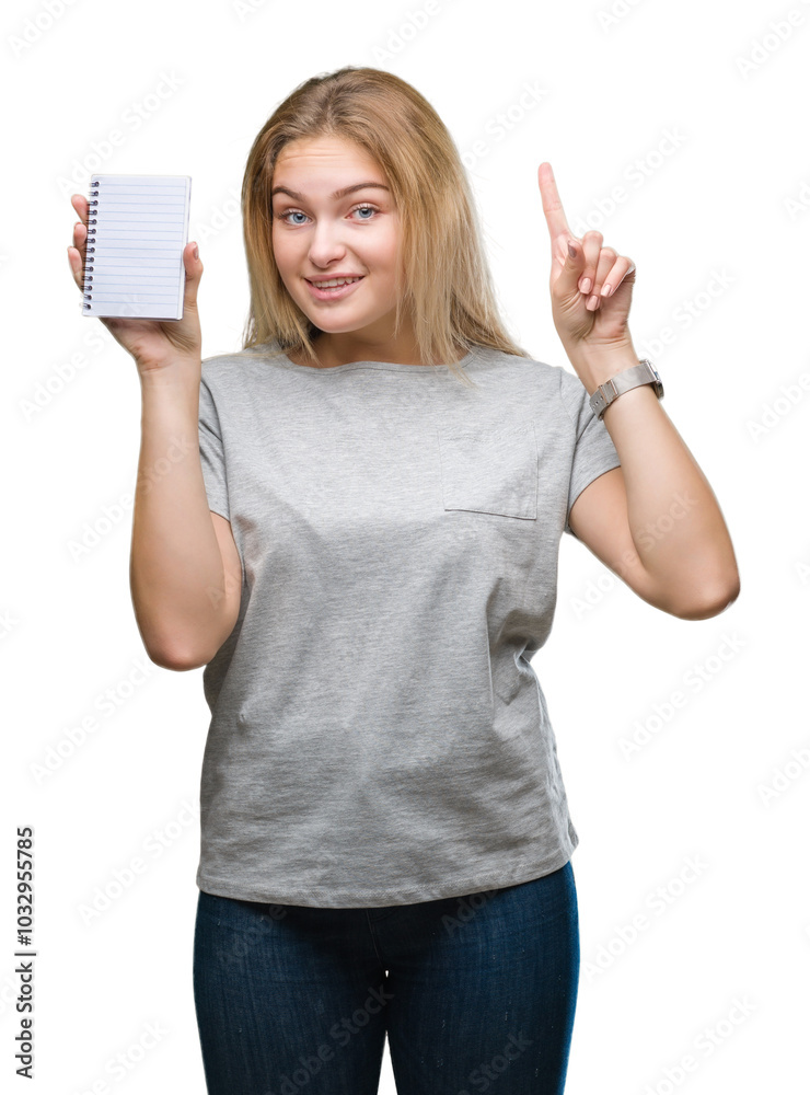 Obraz premium Young caucasian woman holding blank notebook over isolated background surprised with an idea or question pointing finger with happy face, number one