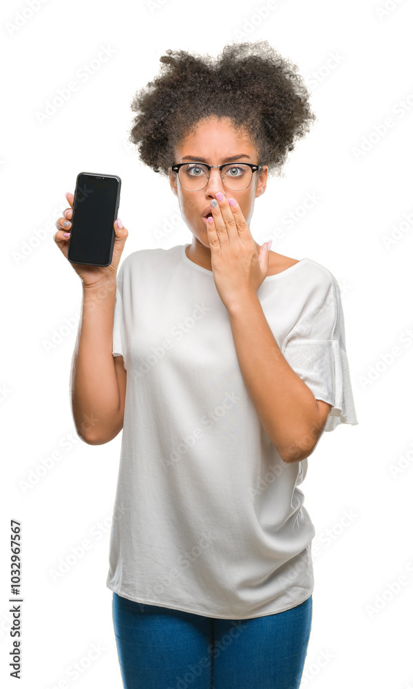 Young beautiful afro american showing smartphone screen over isolated background cover mouth with hand shocked with shame for mistake, expression of fear, scared in silence, secret concept Young beautiful afro american showing smartphone screen over isolated background cover mouth with hand shocked with shame for mistake, expression of fear, scared in silence, secret concept