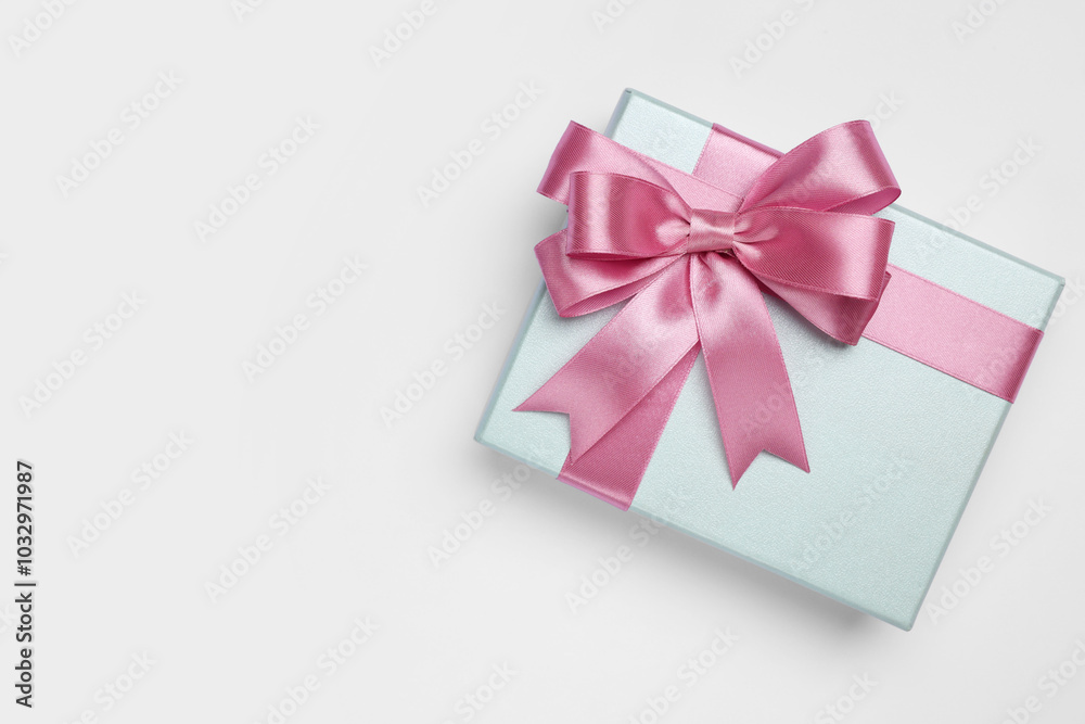 Gift box with pink bow on light grey background, top view. Space for text Gift box with pink bow on light grey background, top view. Space for text