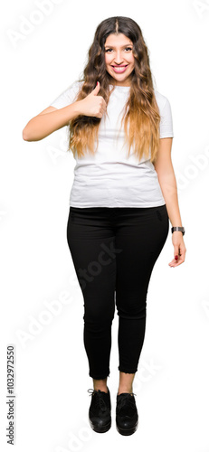 Young beautiful woman wearing casual white t-shirt doing happy thumbs up gesture with hand. Approving expression looking at the camera showing success.