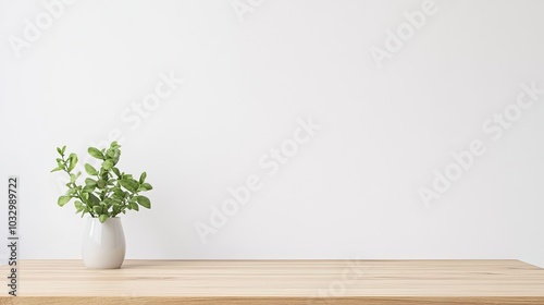 Wooden tabletop with a white vase and green leaves against a minimalist white wall, ideal for product display in a clean, modern setting. Perfect for showcasing home decor or lifestyle products.