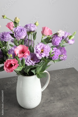 Vase with beautiful eustoma flowers on grey table