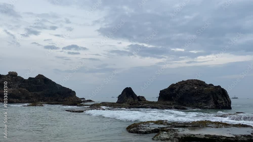 Rocky coastline with ocean waves and an overcast sky at dusk, creating a tranquil seascape scene, perfect for nature and coastal landscape content. Rocky coastline with ocean waves and an overcast sky at dusk, creating a tranquil seascape scene, perfect for nature and coastal landscape content.