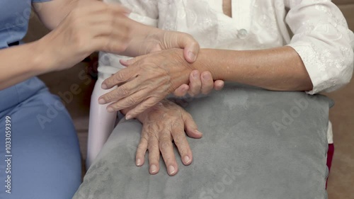 Female caregiver assisting massage and apply lotion on elderly hand for moistering dry skin
