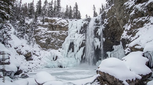 Frozen waterfall cascading down a cliff face in a snowy forest.