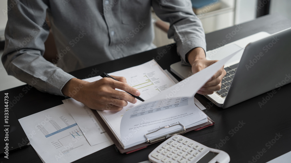 Asian business man holding paper document calculating tax insurance managing budget Asian business man holding paper document calculating tax insurance managing budget