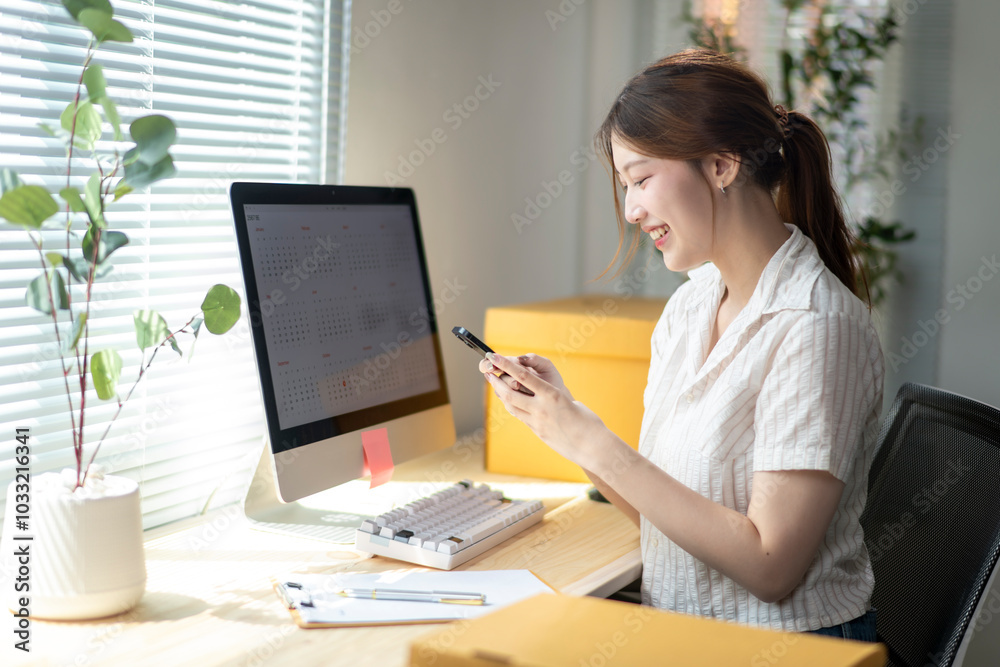 A woman is sitting at a desk with a computer monitor and a cell phone A woman is sitting at a desk with a computer monitor and a cell phone