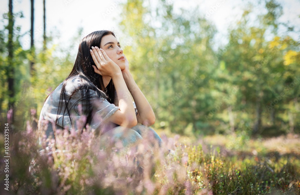 A young woman sits peacefully in a sunlit forest clearing, enjoying nature and reflecting on her thoughts during a bright afternoon A young woman sits peacefully in a sunlit forest clearing, enjoying nature and reflecting on her thoughts during a bright afternoon