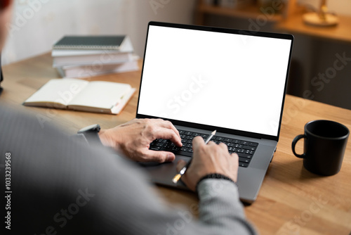 Wallpaper Mural Close-up image of a man working on laptop computer at a table, typing on the laptop keyboard. the laptop with a white screen mockup Torontodigital.ca