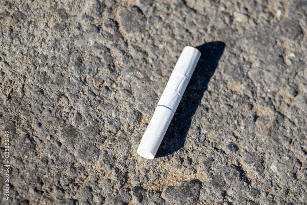 A cigarette butt is laying on the ground A cigarette butt is laying on the ground
