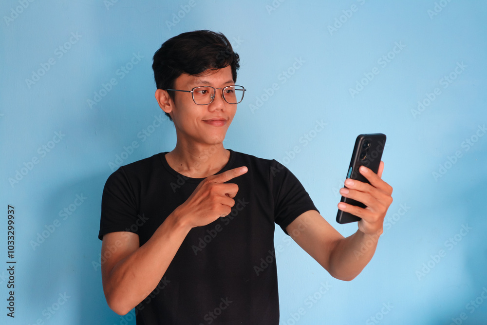 Young Asian man looking his mobile phone with happy expression Young Asian man looking his mobile phone with happy expression