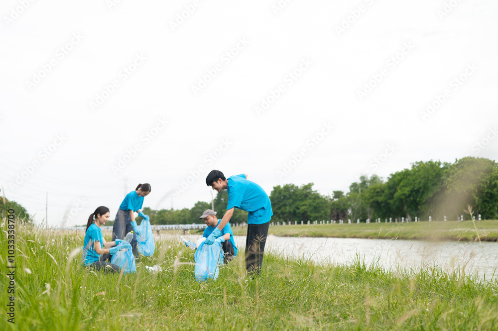 Fototapeta premium A group of happy volunteers cleaned up the riverside by collecting garbage into garbage bags and separating plastic waste from water bottles. Help keep nature clean. Reduce environmental pollution