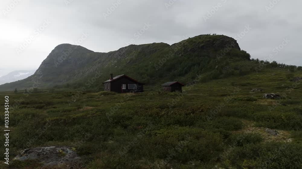 Picturesque aerial view of a wood cabin nestled on a grassy mountain hill, surrounded by serene natural beauty and tranquility. orbit motion shot Picturesque aerial view of a wood cabin nestled on a grassy mountain hill, surrounded by serene natural beauty and tranquility. orbit motion shot
