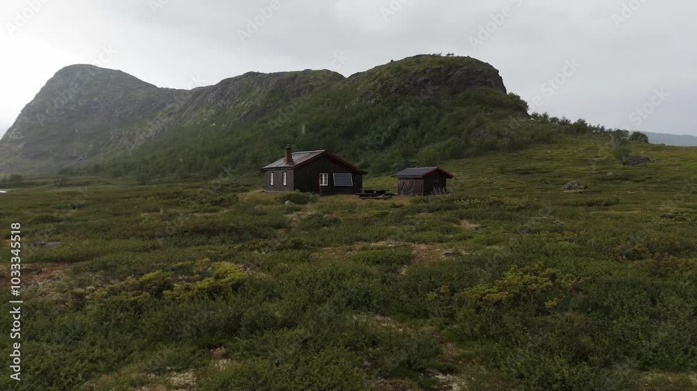 Aerial view of a wood cabin nestled on a grassy mountain hill, surrounded by serene natural beauty and tranquility. orbit motion shot Aerial view of a wood cabin nestled on a grassy mountain hill, surrounded by serene natural beauty and tranquility. orbit motion shot