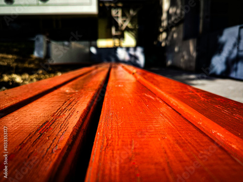 A bench with a red top is shown in a close up. The bench is made of wood and has a rustic look. photo