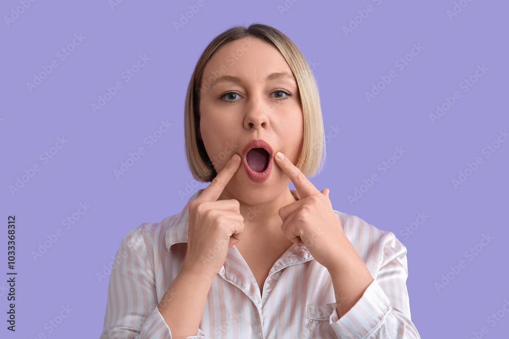 Woman doing face building exercise on lilac background Woman doing face building exercise on lilac background