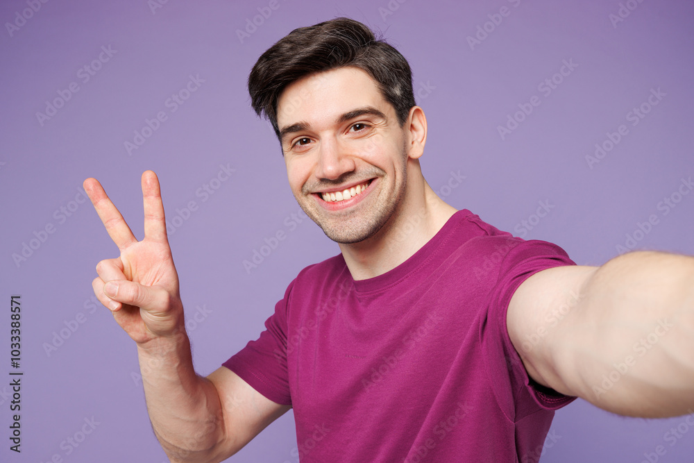 Close up young Caucasian man he wears violet t-shirt casual clothes doing selfie shot pov on mobile cell phone show v-sign isolated on plain pastel light purple background studio. Lifestyle concept. Close up young Caucasian man he wears violet t-shirt casual clothes doing selfie shot pov on mobile cell phone show v-sign isolated on plain pastel light purple background studio. Lifestyle concept.