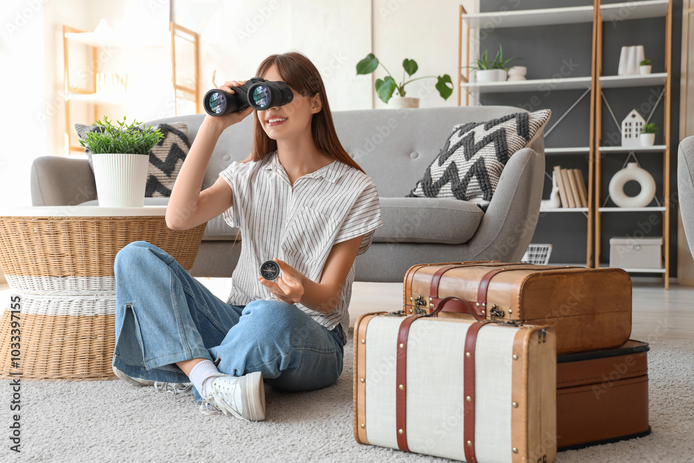 Obraz premium Female tourist with compass looking through binoculars at home