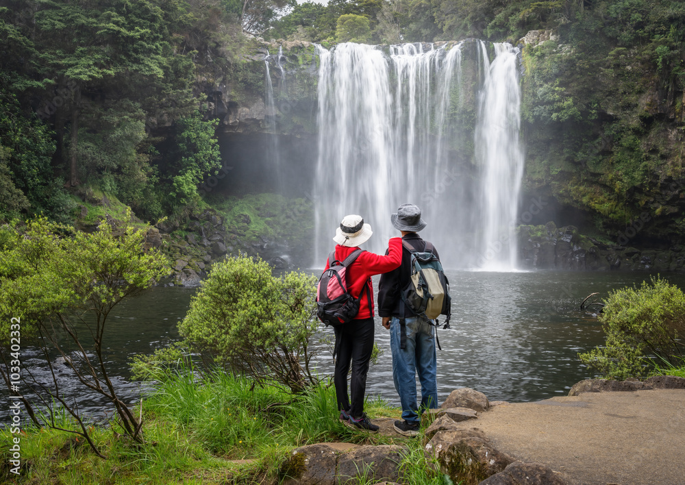 Couple enjoying the view of Rainbow Falls on the Kerikeri river. Northland. New Zealand.