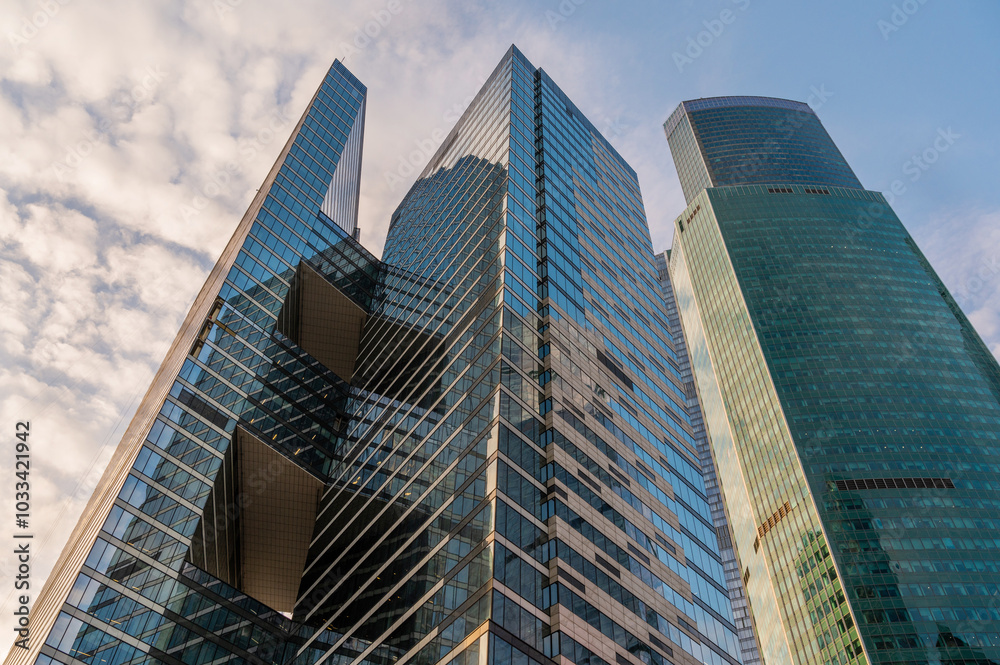 Angled view of modern skyscrapers in business district against blue sky. Looking Up high-rise office buildings. Angled view of modern skyscrapers in business district against blue sky. Looking Up high-rise office buildings.