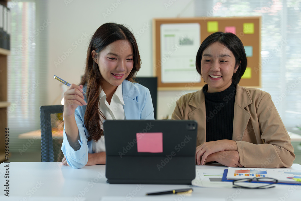 Two young businesswomen pointing to plans, statistics, and data graphs and explaining the conditions of their partnership, happily acknowledging their turnover and income during negotiations. Two young businesswomen pointing to plans, statistics, and data graphs and explaining the conditions of their partnership, happily acknowledging their turnover and income during negotiations.