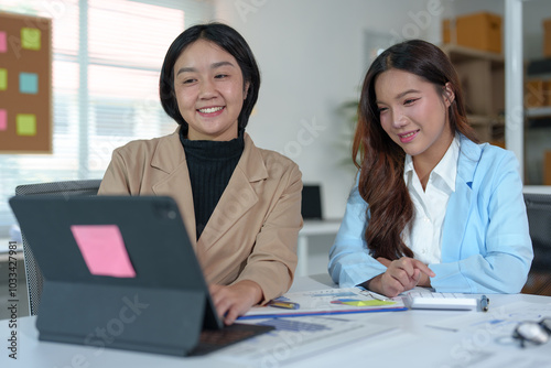 Two Asian businesswomen rejoicing over business success, smiling and expressing joy. Success in starting an online business partner teamwork concept.