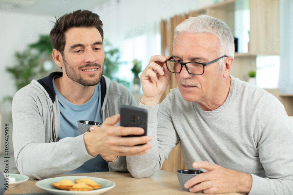 joyful elderly man and son talking on smartphone joyful elderly man and son talking on smartphone