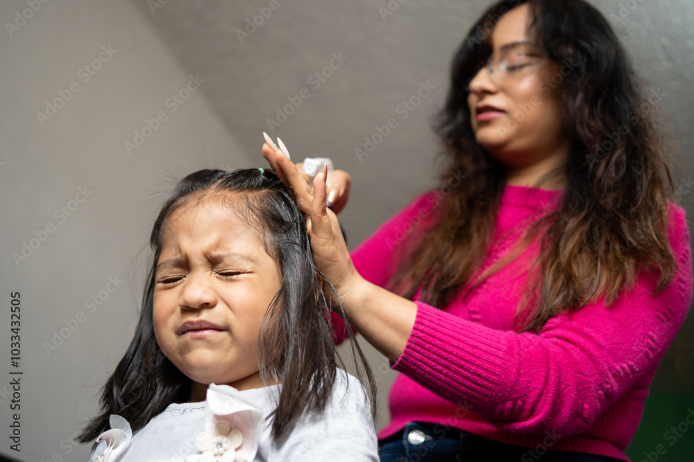 Fototapeta premium Mexican girl angry while her mother combs her hair