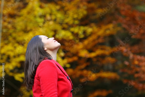 Woman in red jacket breathing deeply fresh air in autumn