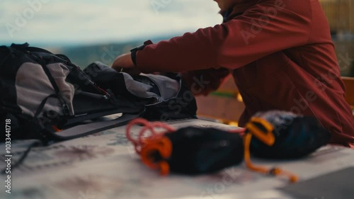 Man packing hiking gear on a table outdoors, preparing for an adventure. Concept of outdoor activities, hiking, adventure, preparation for outdoor exploration