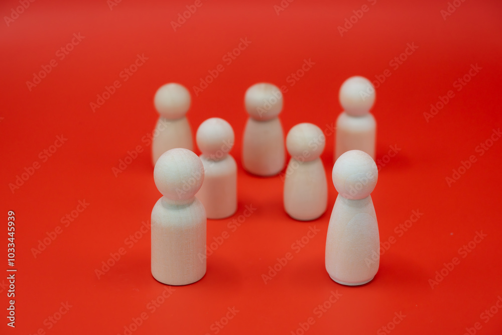 This captivating image portrays a group of white wooden figures gathered together against a vibrant red background. This captivating image portrays a group of white wooden figures gathered together against a vibrant red background.