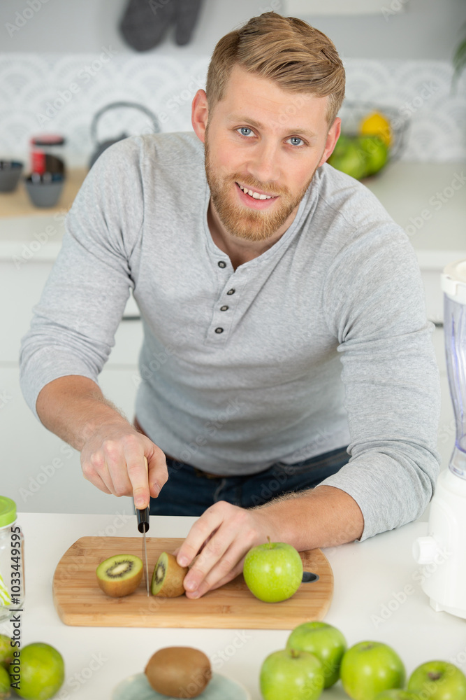 Fototapeta premium happy man cut with a knife a kiwi fruit
