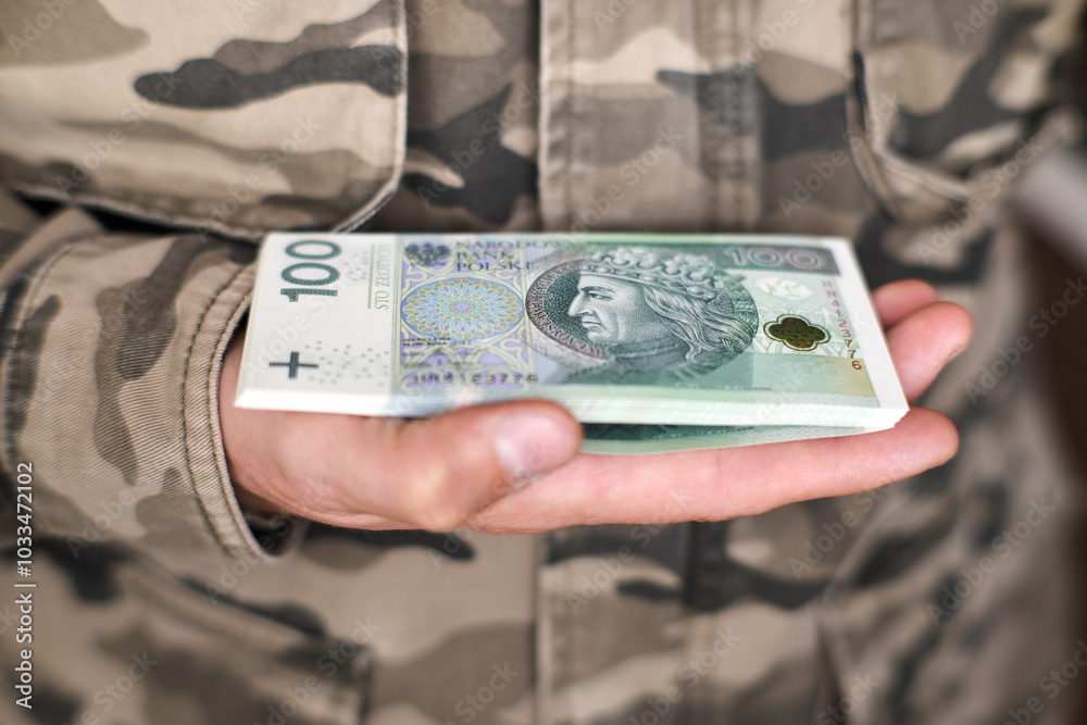 Army, military investments. A soldier holding Polish banknotes.