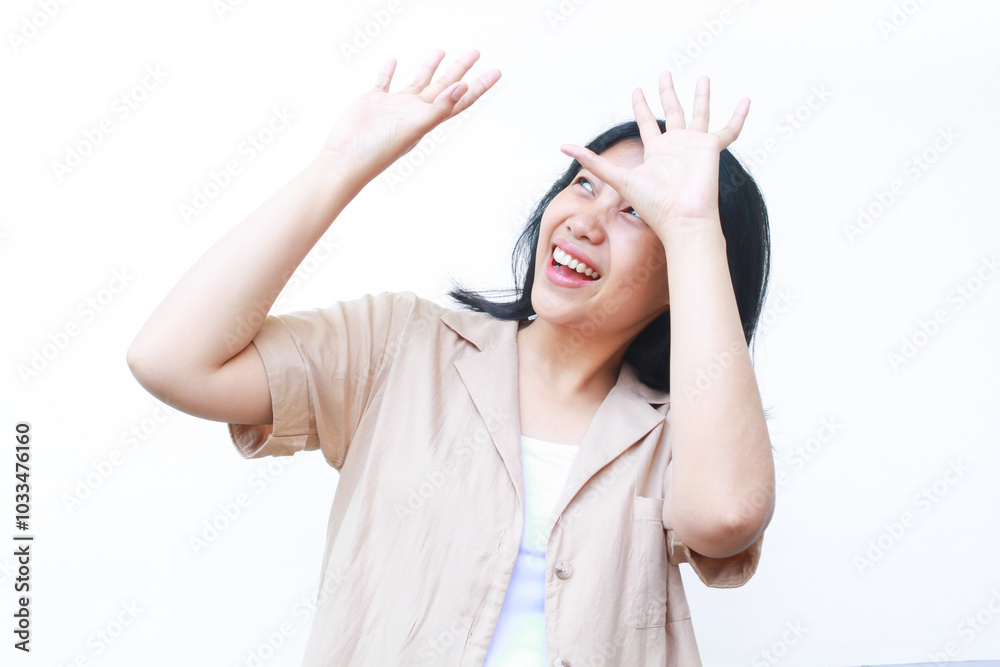 surprised asian woman raising hand over her head and looking up wearing casual brown clothes isolated on white background surprised asian woman raising hand over her head and looking up wearing casual brown clothes isolated on white background