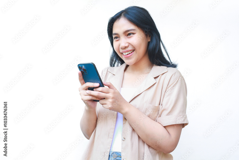 excited asian woman using smartphone and looking away wearing casual brown isolated on white excited asian woman using smartphone and looking away wearing casual brown isolated on white