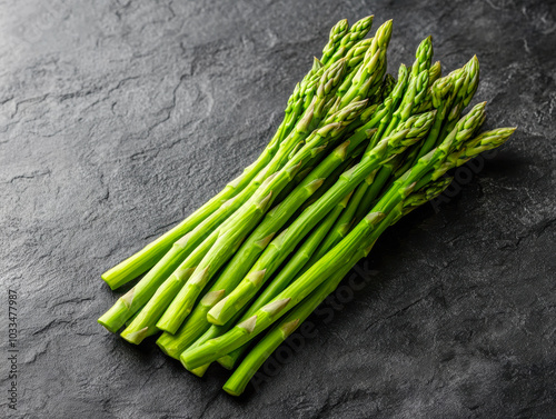 Fresh green asparagus stalks isolated on a dark stone background for culinary use and healthy meal preparation