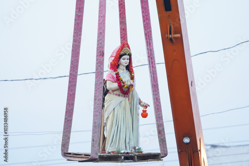 Durga Idol Transport with Crane for Visarjan, Durga Idol Before Immersion by Crane at Kund, Crane Lifting Durga Idol for Visarjan Ritual, Durga Visarjan Preparation Using Crane Stock Photo.
 photo