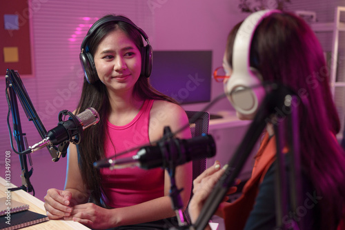 Two beautiful women chat while co-hosting an audio broadcast in a home studio. Recording internet podcasts for social media channels Ideas for creating online work.