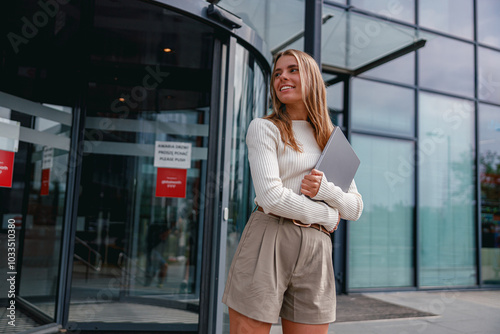 A Young Professional Woman Standing Confidently Outside a Stylish Modern Office Building