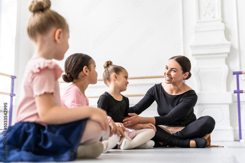 Female professional teacher instructing group of young ballerinas o classical dance indoors Female professional teacher instructing group of young ballerinas o classical dance indoors