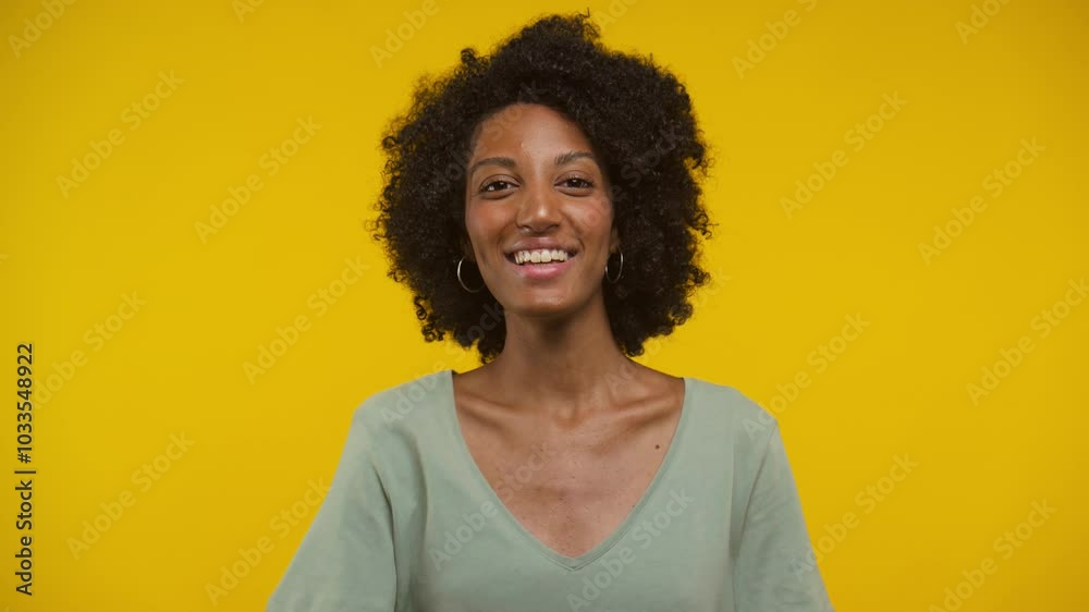Smiling Woman Celebrating Success Against Bright Yellow Background Smiling Woman Celebrating Success Against Bright Yellow Background
