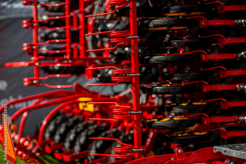 Red industrial agriculture farming machinery close up of details with wheels and mechanisms Red industrial agriculture farming machinery close up of details with wheels and mechanisms